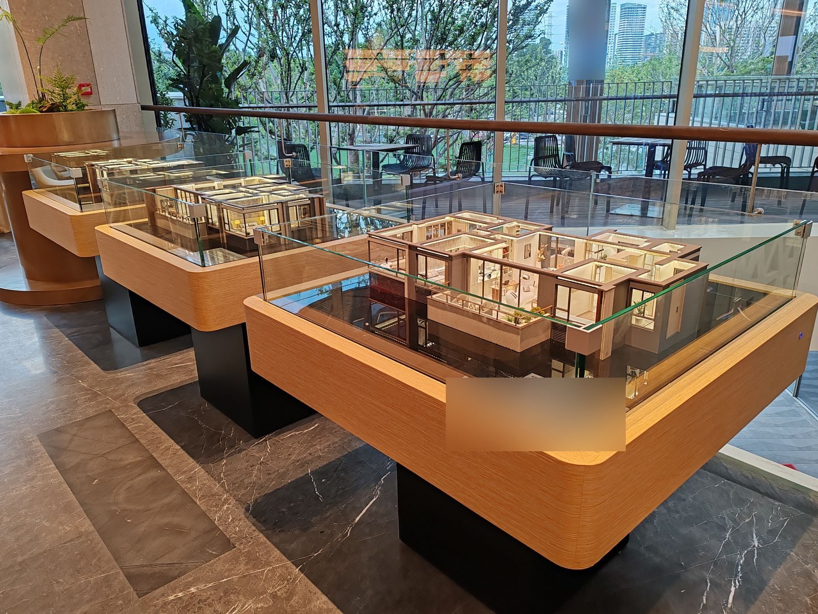 Residential unit layout models displayed under glass covers on a showroom table