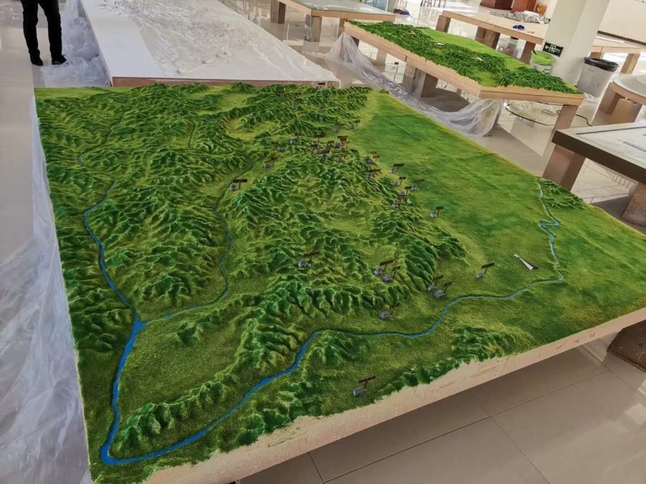 Large terrain relief model laid out on a workshop table